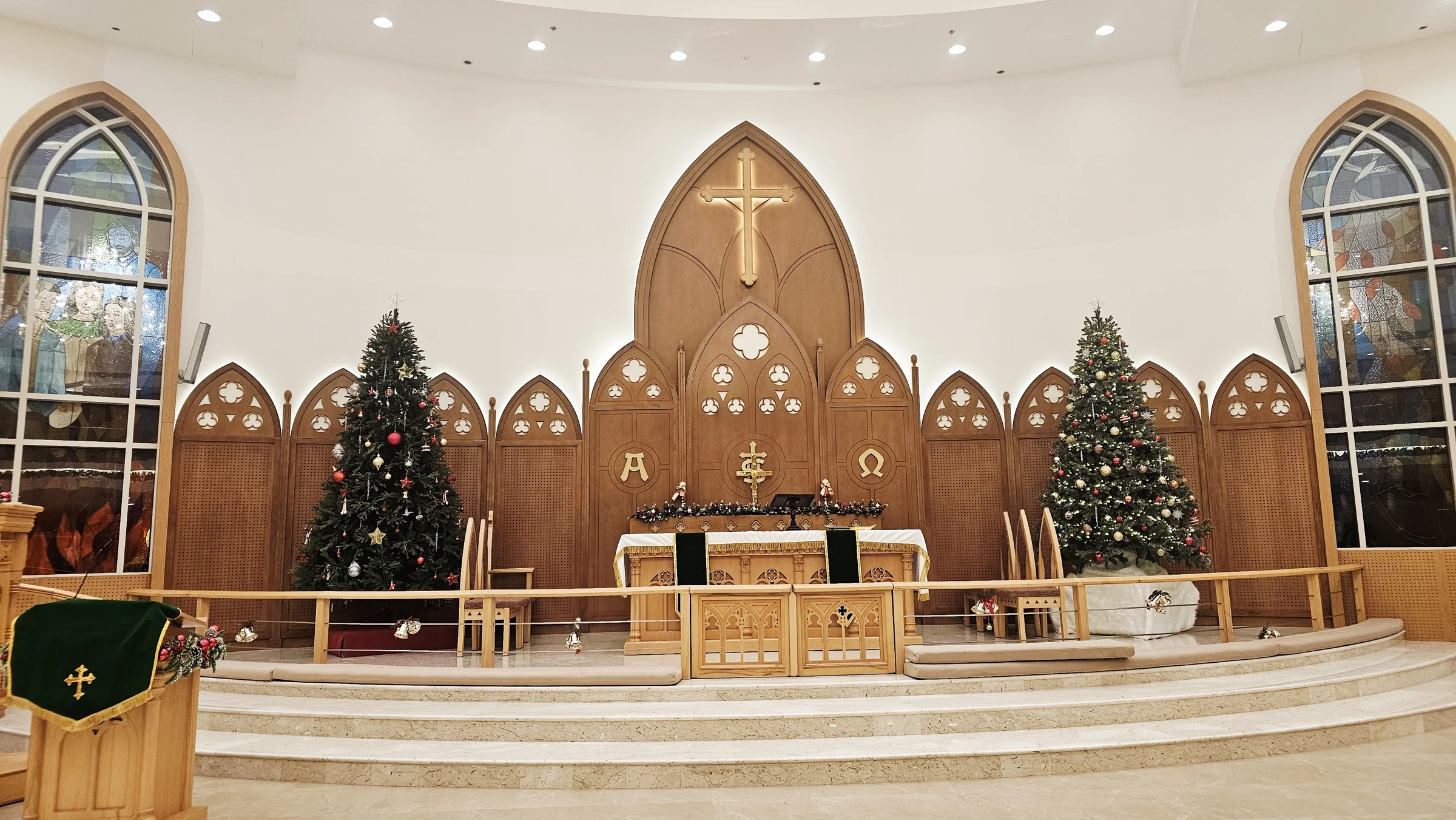 The oak altar, illuminated cross and stained-glass windows inside our church